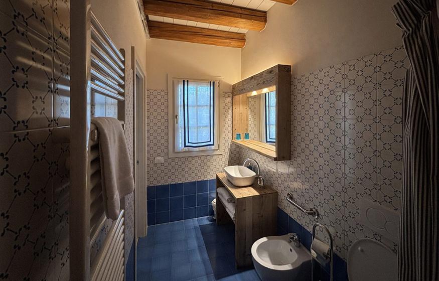 Bagno rustico con travi in legno, piastrelle decorate e lavabo moderno.