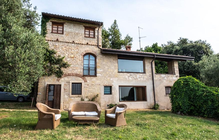 Casale in pietra con mobili da giardino, immerso nel verde.